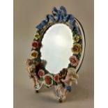 A Dresden oval dressing table mirror decorated with bows, flowers and cherubs, 30cm