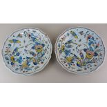 A pair of French faience pottery plates decorated with birds, insects and cornucopias of flowers