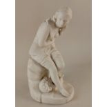 A Parian ware figure of a young woman in 18th century pastoral costume, seated on a rocky outcrop