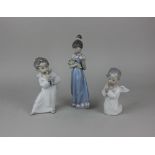 Three Lladro porcelain figures comprising a girl holding flowers 21.5cm high, a musician cherub 17cm