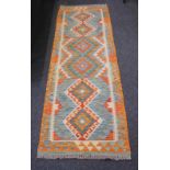 A modern Kilim style runner rug with repeat diamond pattern on orange ground 190cm by 62cm