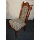 A Victorian oak nursing chair with scroll carved cresting rail above turned supports and padded