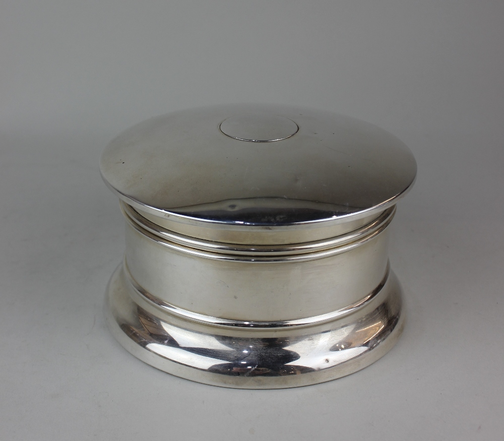 An early 20th century silver circular dressing table box with domed hinged top with mirror inset