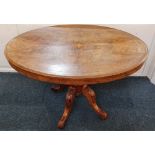 A Victorian inlaid walnut oval table on baluster stem and four carved foliate legs and castors,