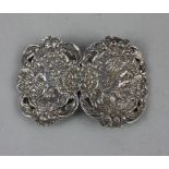 A Victorian nurses silver belt buckle in two pierced oval sections embossed with cherubs and