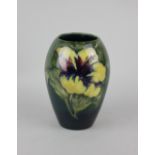 A Moorcroft pottery Hibiscus pattern vase decorated with red and yellow flowers on blue green ground