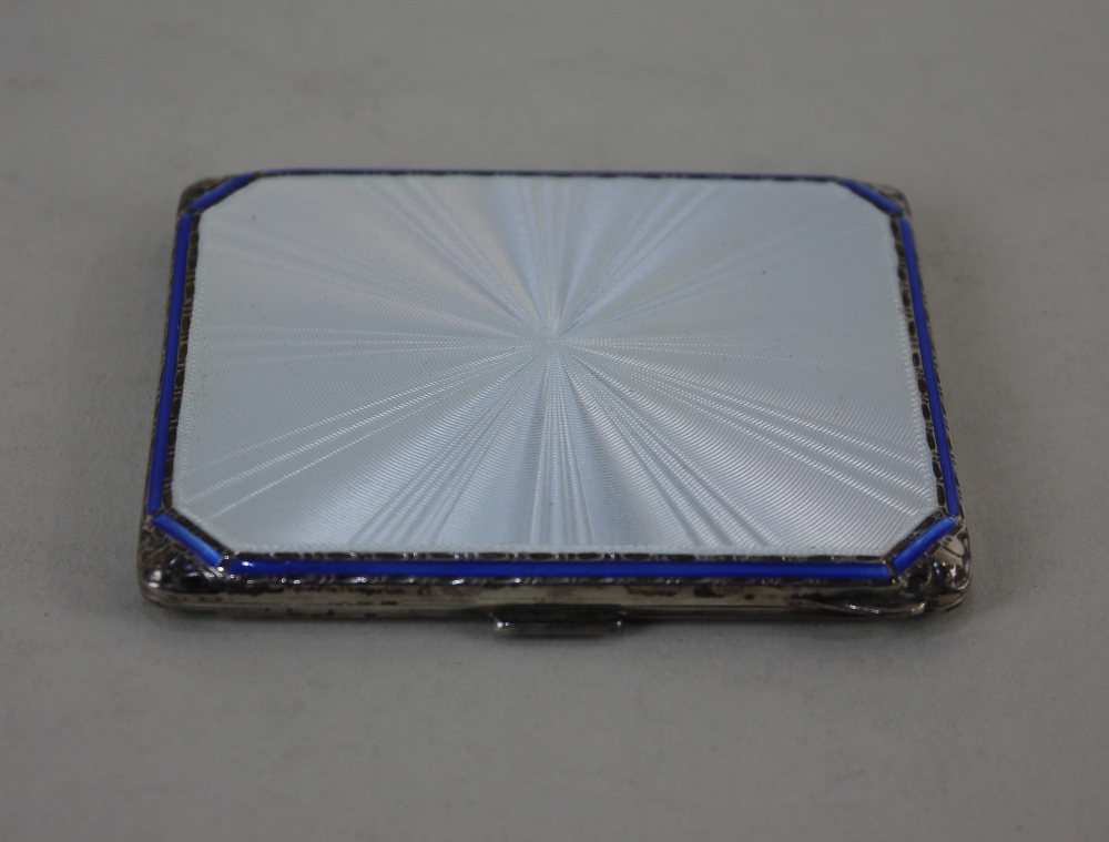 A George VI silver cigarette case with silver guilloche and blue enamelled lid and gilt interior