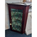 A mahogany corner wall cupboard with glazed panel door enclosing green painted interior with three