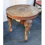 An Eastern carved hardwood occasional table with circular top on elephant carved supports with