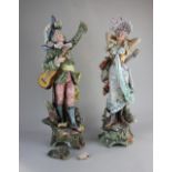 A pair of Majolica figures of musicians, the man with a feathered hat and guitar, the woman with a