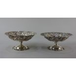 A pair of sterling silver pedestal dishes with lobed centres and floral and scroll embossed