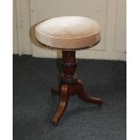 A Victorian mahogany piano stool the adjustable revolving seat on turned stem to outswept tripod