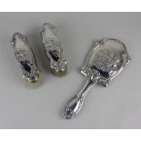 An Edward VII silver three-piece dressing table set of handmirror and two brushes, with embossed