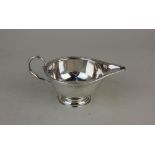 A George V silver sauce boat with cast foliate border on circular pedestal base, maker SW Smith & Co