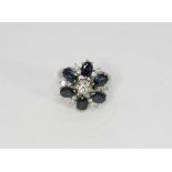 A teal sapphire and diamond cluster ring, the central brilliant cut diamond claw set with a