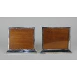 A pair of George V rectangular silver menu holders / photo frames on loaded plinth bases with