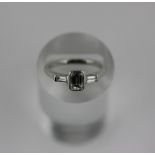 A diamond three stone ring, in a rubover setting with a central baguette diamond with smaller stones