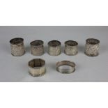 Two pairs of Indian white metal serviette rings and another single napkin ring with embossed