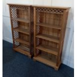 A pair of modern pale wood open bookcases, with fretwork cornice and side panels enclosing three