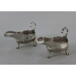 A pair of Victorian silver sauce boats demi-reeded with flying scroll handles on three scroll