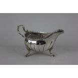 A Georgian Irish silver sauce boat fluted and embossed decoration on three shell and hoof feet,