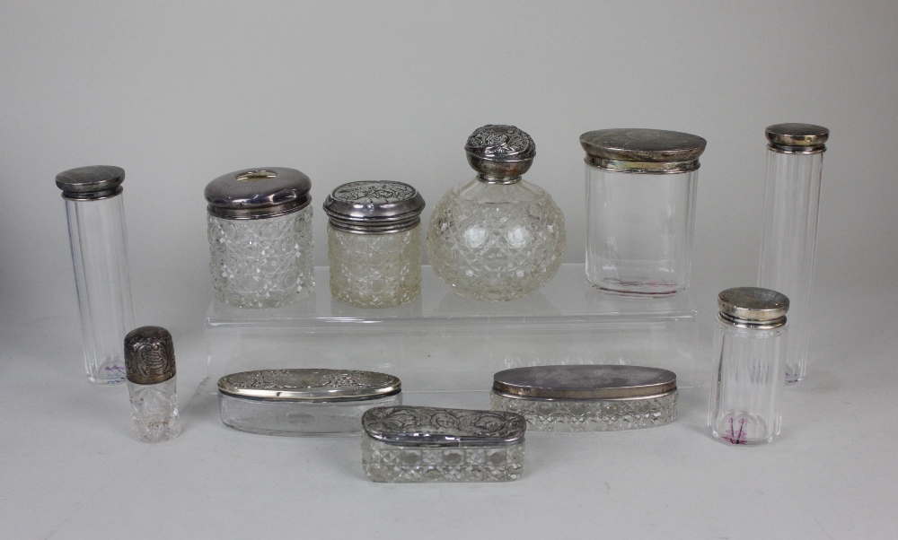 A collection of eleven early 20th century silver topped glass dressing table jars and bottles (a/f)