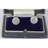 A pair of diamond cluster earrings, each centred with a brilliant round cut diamond