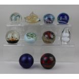 A collection of ten coloured glass paperweights to include Caithness Seadance, Ronneby Sweden,