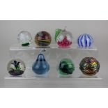 A collection of eight coloured glass paperweights to include Caithness Windfall and Isle of Wight