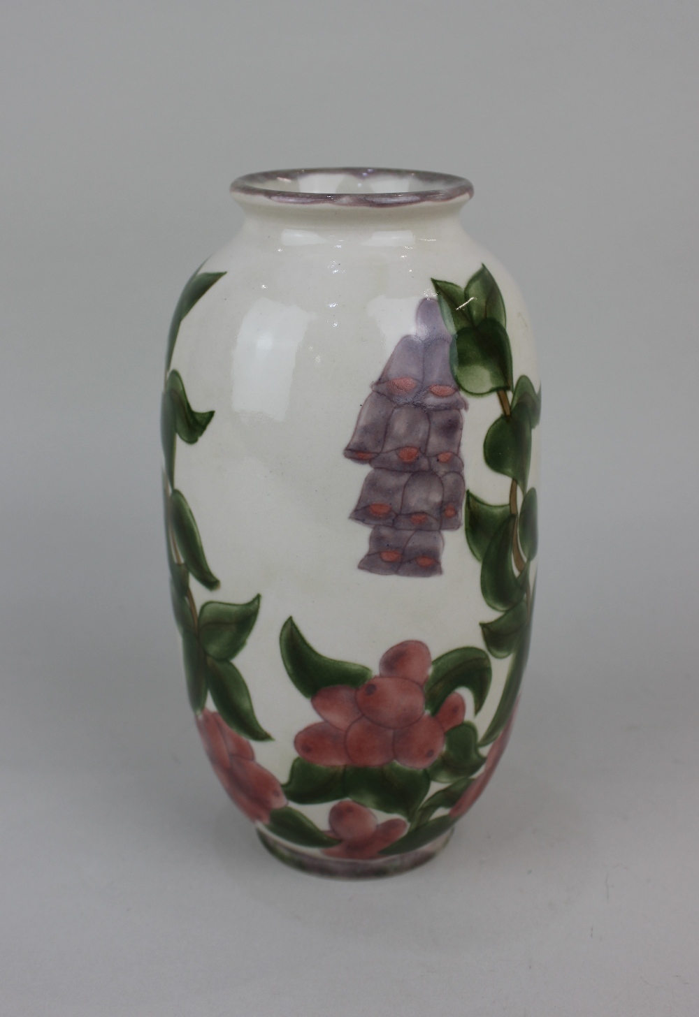 A Cobridge stoneware vase decorated with foxgloves and berries on cream ground 22cm high