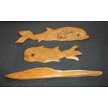 Two carved wooden wall plaques of whales the largest with a crouching figure of Jonah 141cm long,