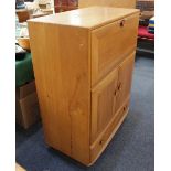 An Ercol light secretaire cabinet with fall front, two cupboard doors and base drawer, on castors,