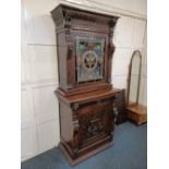 A 19th century Flemish style carved oak cabinet the top section with coloured leaded glass door,