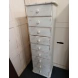 A white painted narrow chest of nine drawers with 'distressing' to edges, on bun feet, 43cm