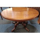 A Victorian mahogany oval looe table with tilting top on baluster stem and four foliate carved