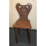 A carved oak hall chair shaped back and seat carved with scaled creatures and skull