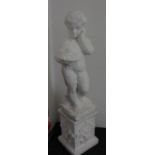 A white painted garden statue of a boy holding a basket of fruit, on plinth base, 103cm
