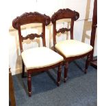 A pair of Victorian dining chairs with scroll carved top and back rail, upholstered seats on
