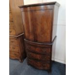 A mahogany bowfront cabinet two doors enclosing two shelves on base with slide and three drawers, on