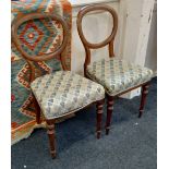 A pair of Victorian balloon back dining chairs with upholstered seats on turned tapered legs