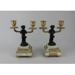 A pair of French bronze and gilt metal two branch candelabra each modelled as a satyr holding