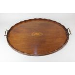 An Edwardian mahogany oval tray inlaid with central shell motif, two brass carrying handles 64cm