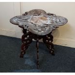 A Chinese carved occasional table the deeply carved shaped top with coiled dragon border on four