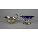 A George V silver sauce boat with flying scroll handle on three shell cast feet, London 1929 and