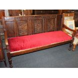 A Victorian oak settle bench with carved panel back (from an 18th century coffer) upholstered