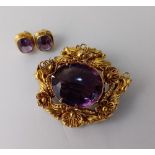 An amethyst brooch, in an ornate foliate mount, with a pair of amethyst ear studs