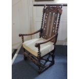 A Charles II style elbow chair with a caned back and seat, the cresting and front rail with carved