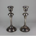A pair of modern silver candlesticks with urn sconces on flared stems and loaded circular bases,