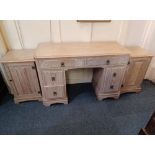 A limed oak part bedroom suite comprising dressing table and pair of bedside cupboards with carved