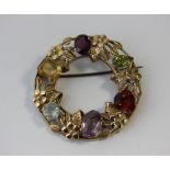 A 9ct gold multi gemset floral circular brooch, set with six vari cut gems including garnet,